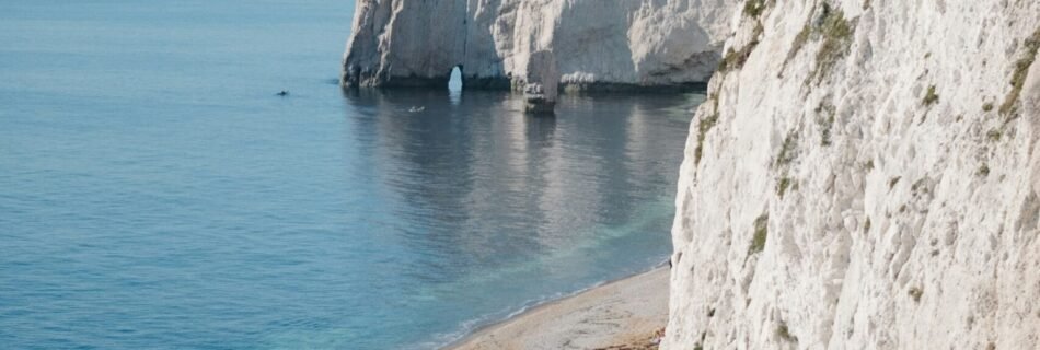 a sandy beach next to a large white cliff